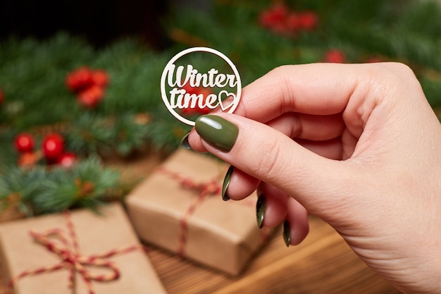 La niña tiene en la mano la inscripción horario de invierno en el fondo de los accesorios navideños