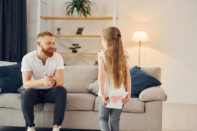 La niña tiene un regalo para el hombre Padre con su pequeña hija está en casa juntos