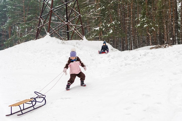 la niña tira del trineo cuesta arriba mientras la otra baja en el bote de hielo