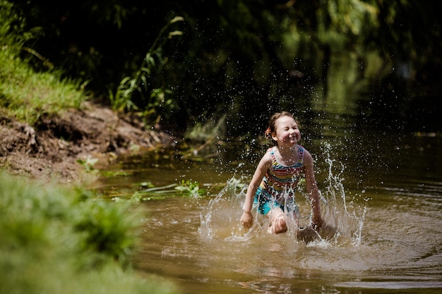 Niña tirando en el agua del lago en verano en un día soleado