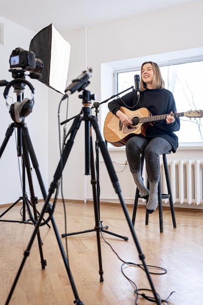 Una niña toca la guitarra grabando video y sonido.