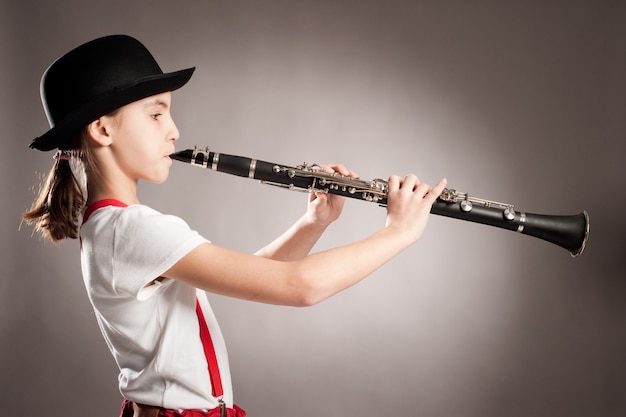 Niña tocando el clarinete en gris