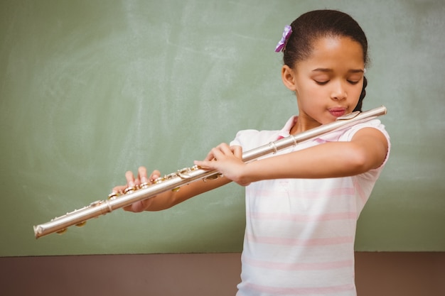 Niña tocando la flauta en el aula