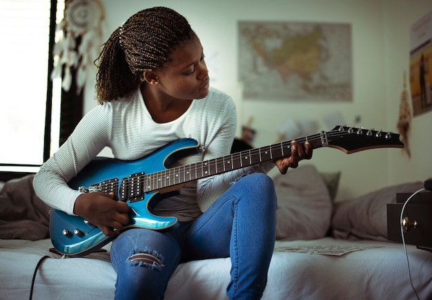 Niña tocando la guitarra eléctrica en su dormitorio