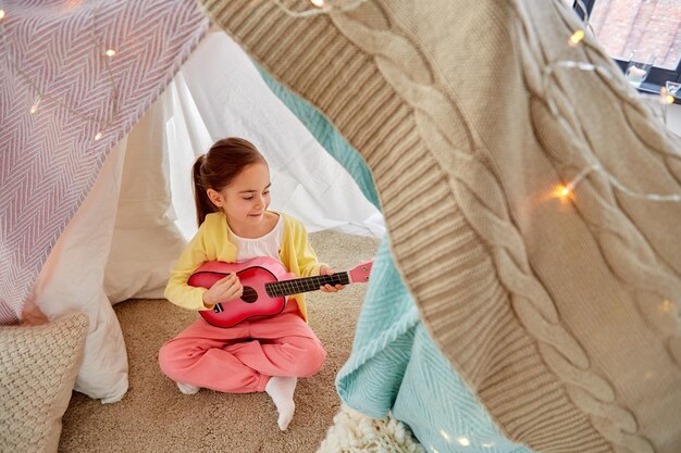 niña tocando la guitarra en la tienda de los niños en casa