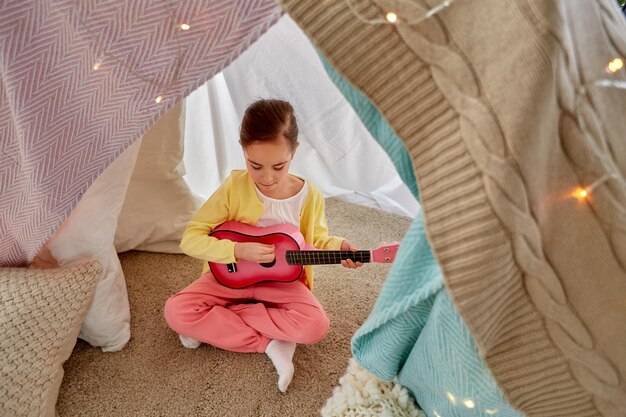 Foto niña tocando la guitarra en la tienda de los niños en casa