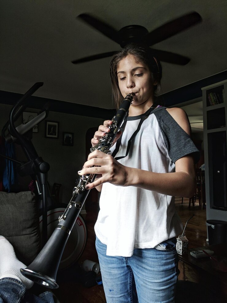Foto niña tocando un instrumento musical mientras está de pie en casa