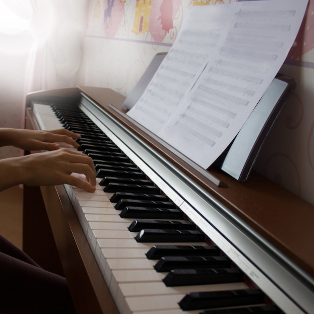 Niña tocando el piano digital. Vista lateral.