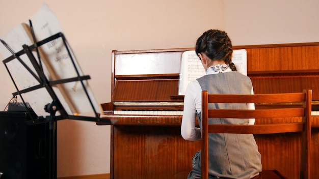 Una niña tocando el piano en la vista posterior de la lección de música