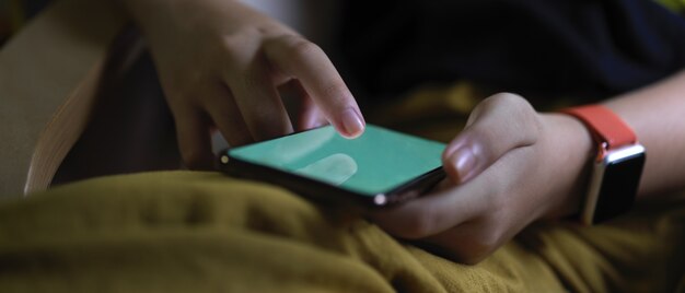 Una niña tocando el teléfono inteligente mientras está sentado con las piernas cruzadas en la sala de estar