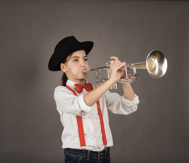 Niña tocando la trompeta en gris