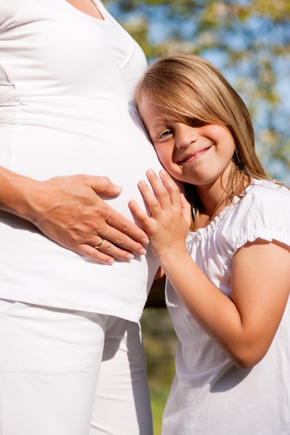 Niña tocando el vientre de la madre embarazada