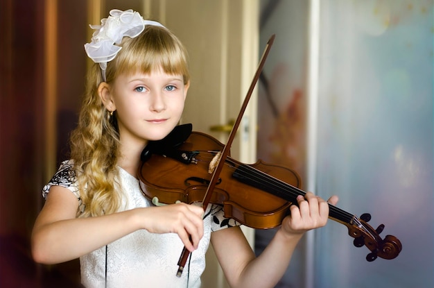 Niña tocando el violín en casa