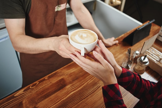 La niña toma un café de un barista. Manos y primer plano de la taza