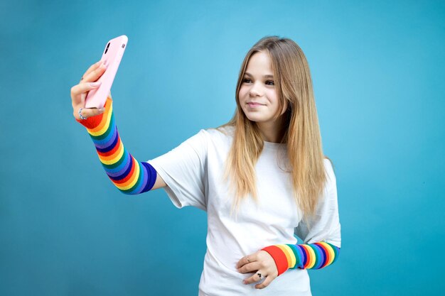 La niña se toma una foto en un teléfono inteligente con un fondo azul.