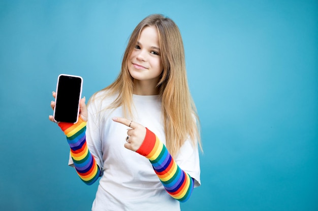 La niña se toma una foto en un teléfono inteligente con un fondo azul.