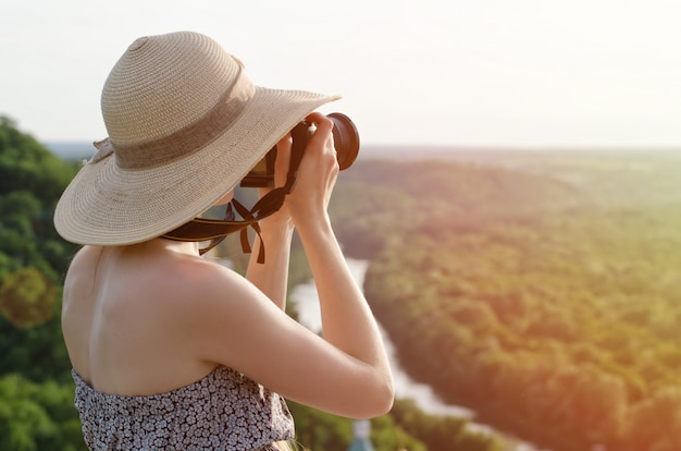 Niña toma fotos contra el bosque y el río