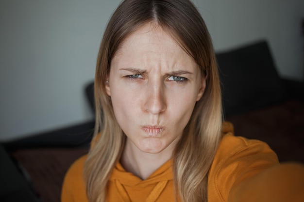 Una niña se toma selfies y mira con enojo a la cámara.