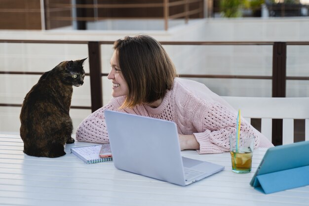 Foto niña trabajando remotamente en la terraza de su casa con su mascota