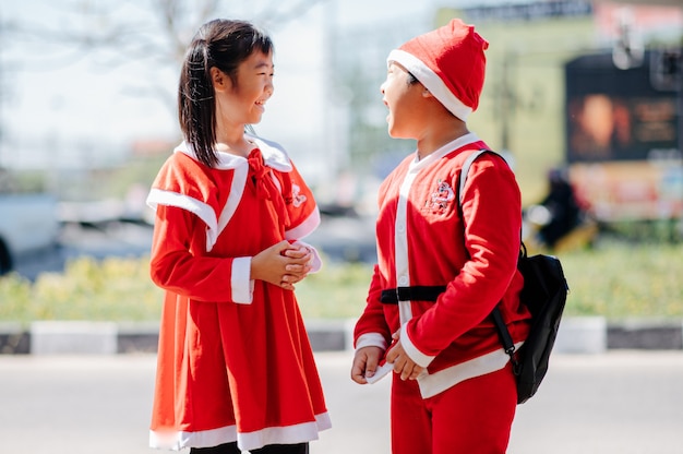 Foto una niña con un traje de arena y un niño con un traje de papá noel juegan felices.