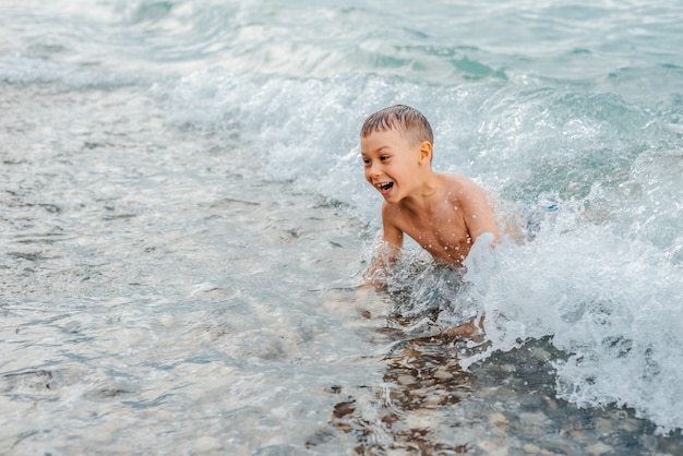 Niña en traje de baño chapoteando sus piernas en el mar