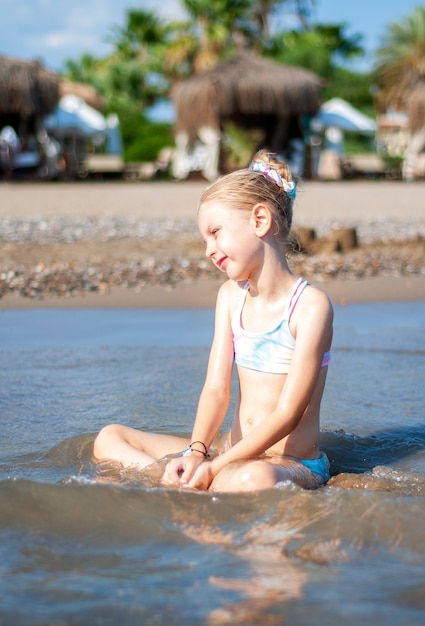 Niña en traje de baño jugando en la playa junto al mar