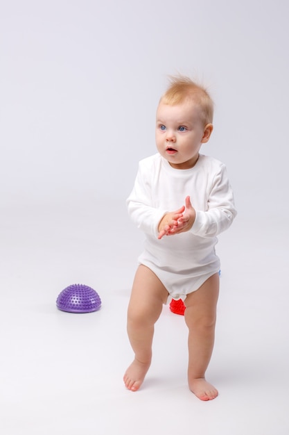 Niña en traje blanco con herramientas de fisioterapia para vaina de equilibrio de pies planos sobre fondo blanco