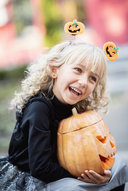 Niña en traje de bruja celebrar Halloween al aire libre y divertirse.