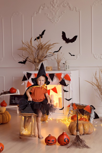 Foto niña en traje de bruja de halloween con calabazas