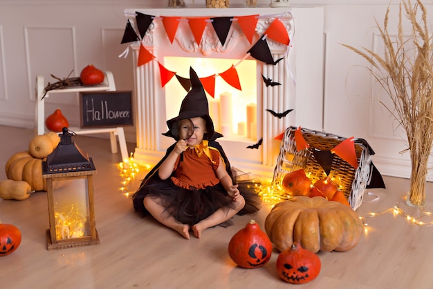 Foto niña en traje de bruja de halloween con calabazas