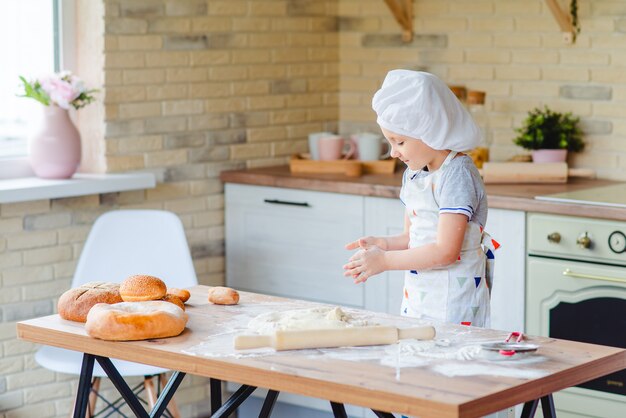 Niña en traje de cocinero cocinando en la cocina