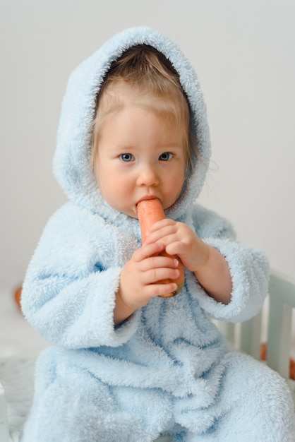 Niña en un traje de conejo comiendo zanahorias.