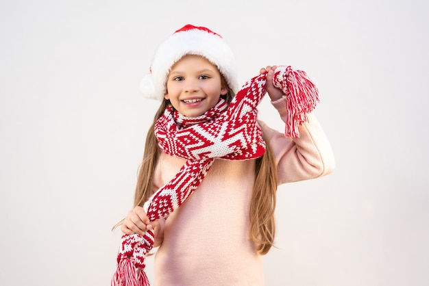 Una niña con un traje de Navidad sostiene un pañuelo con ambas manos y está muy feliz con la Navidad.