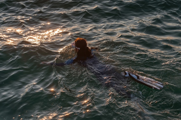 Una niña en un traje de neopreno buceando en el mar.