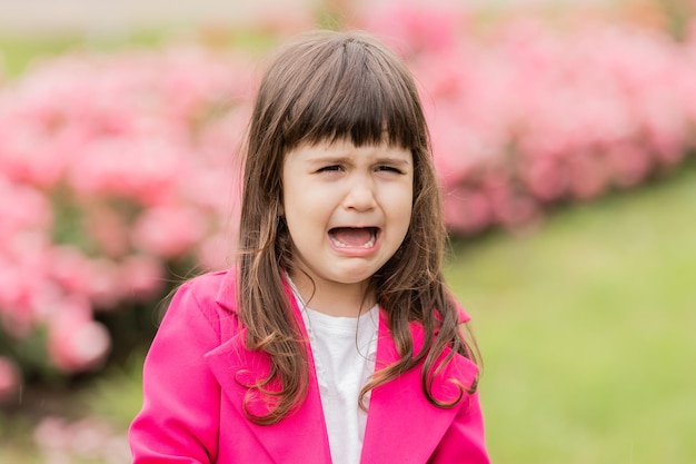 una niña en un traje rosa brillante está llorando en la calle