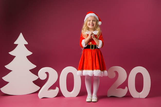 Niña en traje de Santa se encuentra con números 2020