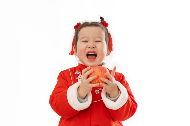 La niña en traje tradicional chino tiene una manzana en la mano