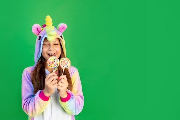 niña en traje de unicornio comiendo Lollipop