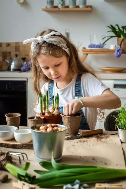 Niña trasplanta flores y plantas de interior un niño en un pañuelo planta bulbos y microvegetales