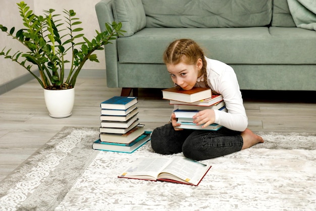 una niña tratando de sostener una pila de libros