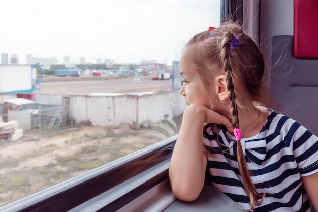 Niña en el tren mira por la ventana