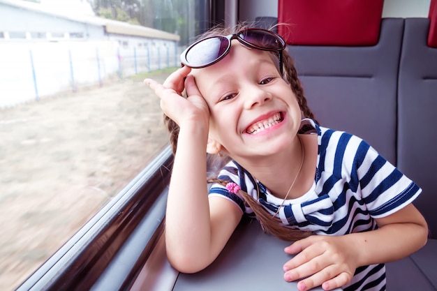 Niña en el tren mira por la ventana