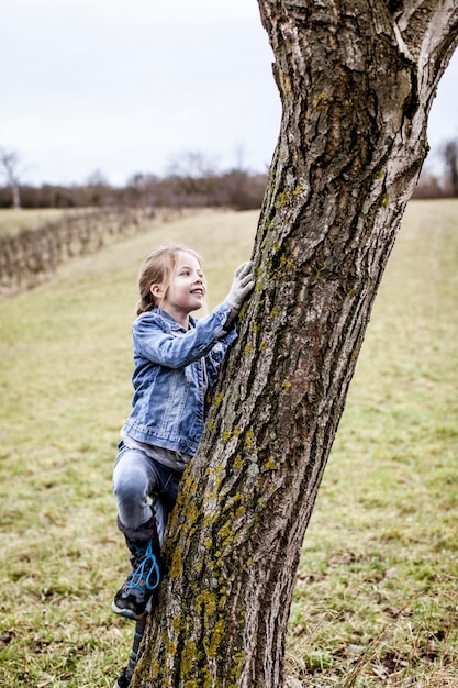 Foto niña trepando a un árbol en el campo