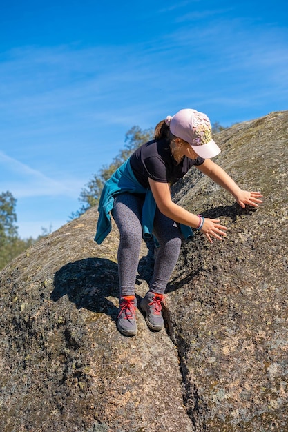 Niña trepando una piedra grande y jugando al aire libre Actividades al aire libre ocio en verano