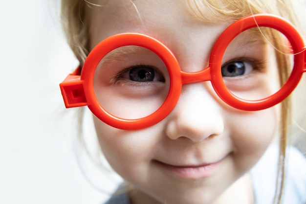 Una niña de tres años con gafas de bebé juega al doctor