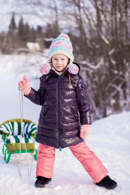 Niña va en trineo en un cálido día de invierno