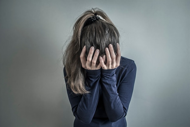 Una niña triste y deprimida sostiene su cabeza. La mujer está llorando.