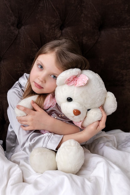 Foto una niña triste está enferma y abraza un juguete en la cama.