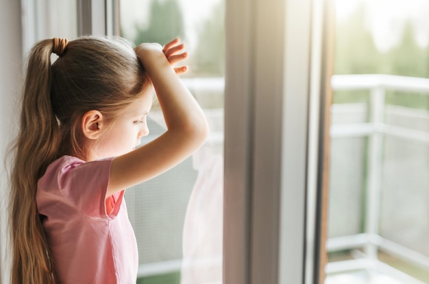 Niña triste mirando por la ventana en casa