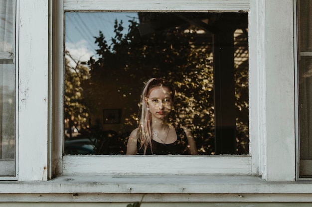 Niña triste mirando por la ventana durante un encierro.